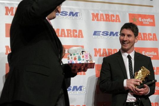 Barcelona's Argentinian forward Lionel Messi (R) poses after receiving the European Golden Boot 2012 award for best European goalscorer of the 2011-2012 season next to Oscar Campillo, director of the Marca sports newspaper, on October 29, 2012 i...