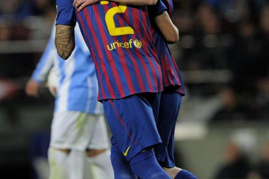 Barcelona's Argentinian forward Lionel Messi (R) is congratuled by his teammate Barcelona's Brazilian defender Daniel Alves (L) after scoring during the Spanish League football match Barcelona vs Malaga at the Camp Nou stadium in Barcelona on Ma...