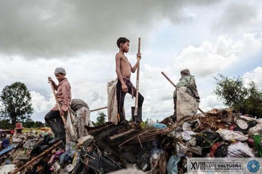 Kon Mai, de 15 años, encima de una montaña de basura. Comenzó a trabajar en el basurero con 12 años y tuvo que dejar de estudiar porque sus padres continuamente necesitaban ir de un lugar a otro buscando trabajo. Ellos también trabajan en e...