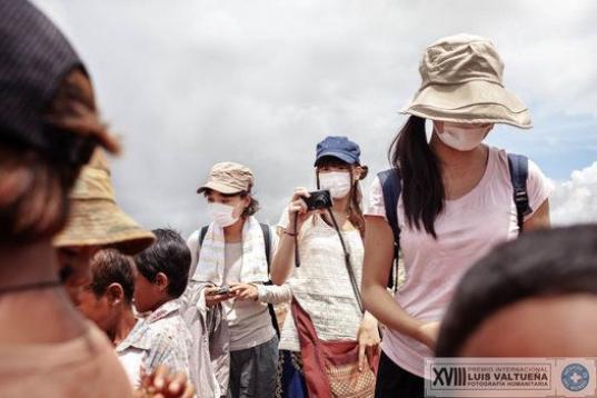 Una turista japonesa tapada con una mascarilla hace fotos a los niños que trabajan en el basurero.