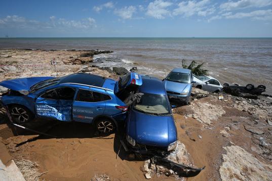 Una pila de coches, destrozados en la orilla por los efectos de la riada