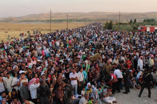 En esta fotografía tomada por funcionarios de la agencia de refugiados de las Naciones Unidas el 15 de agosto del 2013 se ve a refugiados sirios cruzando la frontera iraquí en el puesto fronterizo de Peshkabour, en Dahuk, para entrar en el sec...