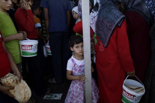 Una niña y otras personas hacen fila para comprar pan y huevos en una tienda en el puesto fronterizo de Bab Al-Salameh, cerca de la localidad siria de Azaz, el lunes 3 de septiembre de 2012. Numerosos desplazados por la violencia en Siria prete...