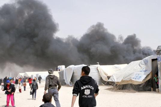 Humo negro se levanta sobre el campamento para refugiados sirios de Zaatari, en el noreste de Jordania, el viernes 8 de marzo de 2013. No hubo víctimas a causa del incendio que destruyó al menos 20 tiendas de campaña, según autoridades de la...