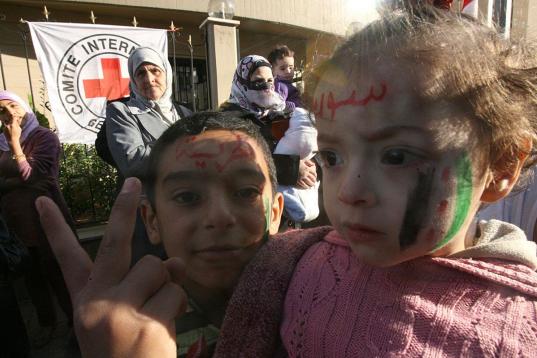 Dos niños sirios refugiados que escaparon con sus familias de la violencia en su país hacen la señal de victoria, con los rostros decorados conla bandera de la revolución siria y la frase en árabe: "Siria, la revolución", durante una manif...