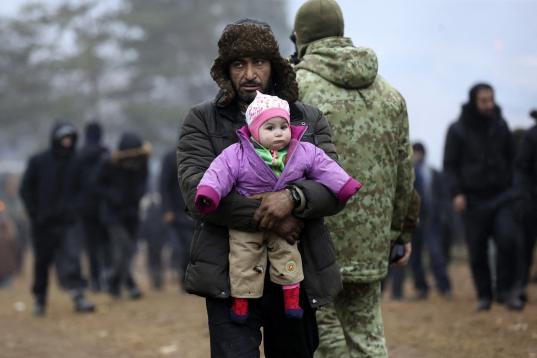 Un hombre abraza a una niña en un campamento improvisado en la frontera entre Bielorrusia y Polonia, en la región de Grodno, ayer domingo.