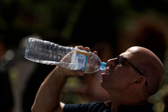 Un turista bebe agua este lunes mientras hace cola para entrar en el Palacio Real de Madrid. 