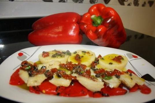 Lleva bacalao desalado, pimientos rojos asados, patata, aceitunas negras, tomate seco, perejil y aceite de oliva. Aquí tienes la receta completa. 