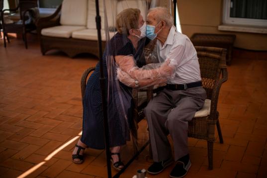 Agustina Cañamero, de 81 años, y Pascual Pérez, de 84, se abrazan y besan a través de plásticos en una residencia de Barcelona, el pasado 22 de junio. 