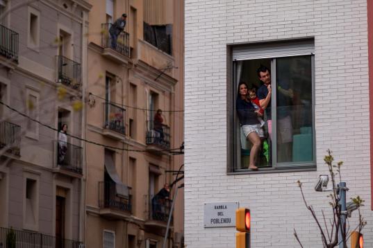 Una familia asomada al balcón durante el confinamiento, en Barcelona. 