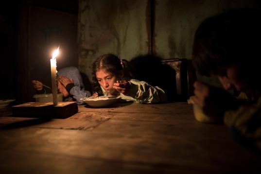 Estiben, Estefany y Javier Aquino cenan a la luz de una vela en el barrio de Nueva Esperanza, Lima, por no tener acceso a electricidad. 