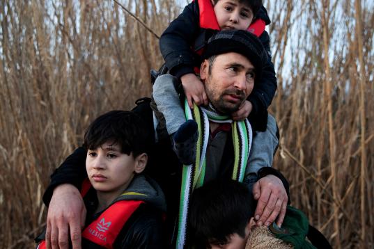 Un hombre llegado desde Afganistán abraza a sus hijos tras llegar a la isla de Lesbos, Grecia. 