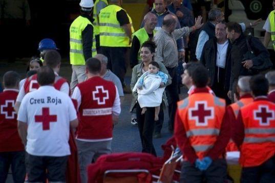 Pasajeros a su llegada al puerto de Palma de Mallorca, mientras trabajadores de la Cruz Roja esperan por si hay heridos.