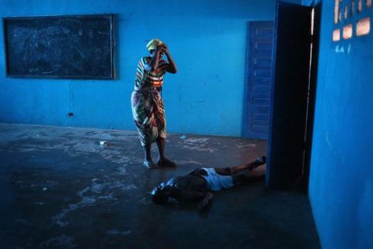 Omu Fereneh llora junto al cuerpo caído de su marido Ibrahim, que se desplomó inconsciente en un ala hospitalaria de ébola en Monrovia (Liberia) el 15 de agosto de 2014.
