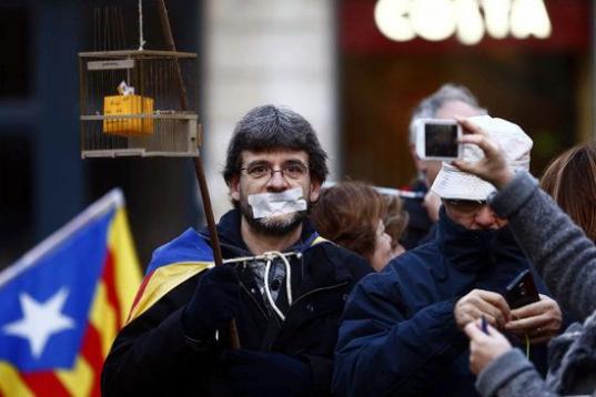 Uno de los asistentes en la concentración en la plaza de Sant Jaume porta una urna enjaulada.