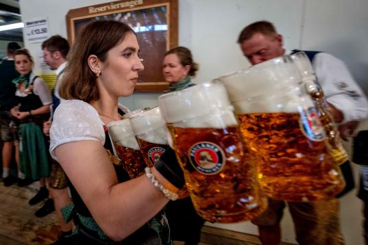 A waiter carries beer in one of the beer tents on the opening day of the 187th Oktoberfest beer festival in Munich, Germany, Saturday, Sept. 17, 2022. (AP Photo/Michael Probst)