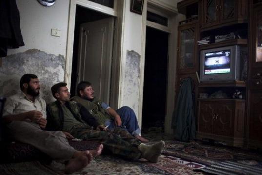 Combatientes de la oposición ven la televisión en un piso de la ciudad de Alepo (Siria)