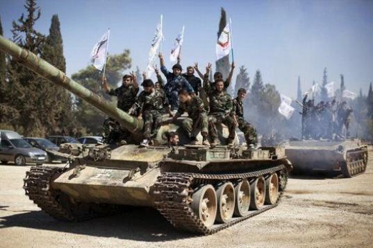 Miembros de las brigadas rebeldes celebrando hacen el símbolo de la victoria con los dedos sobre un tanque. 