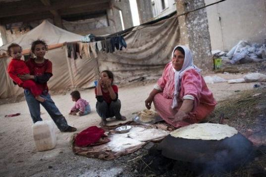 Una mujer desplazada prepara pan para sus niños en una fábrica abandonada en la ciudad de Alepo, Siria. 