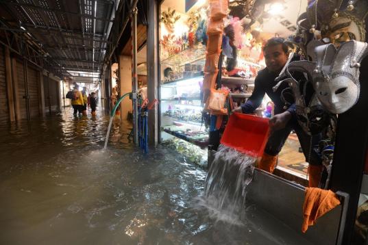 Un tendero achica agua de su tienda en Venecia, Italia. Seis regiones italianas están en alerta roja por el fuerte temporal y las intensas lluvias que están azotando el país en las últimas horas y que han provocado el...