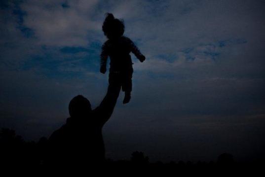 Sujetándola con una mano por encima de su cabeza, un padre juega con su hija en el centro para refugiados y migrantes de Sid (Serbia). El país es un territorio de tránsito en el éxodo de los refugiados hacia el norte de Europa. 