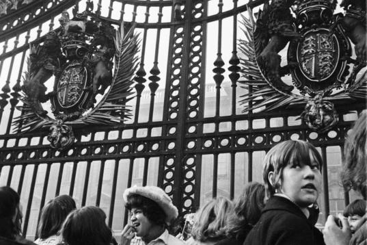 Un fan de Los Beatles escala la puerta del Palacio de Buckingham mientras la reina Isabel II nombra al grupo Miembro de la Orden del Imperio Británico en octubre de 1965.