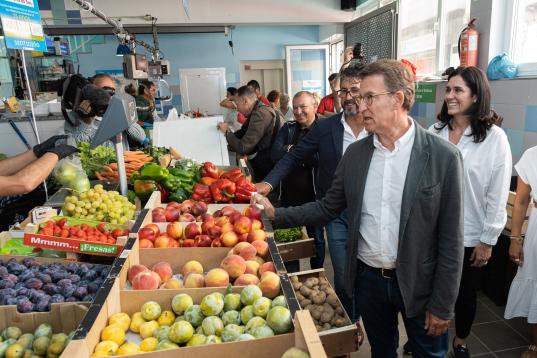 Feijóo comprobando el estado de varias piezas de fruta en una visita a la plaza de abastos de Portosín (Porto do Son, A Coruña).