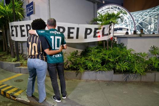 Football fans stand in front of a banner reading "Eternal King Pele" outside the Albert Einstein Israelite Hospital, where the Brazilian football legend died after a long battle with cancer, in Sao Paulo, Brazil, on December 29, 2022. - Brazilia...