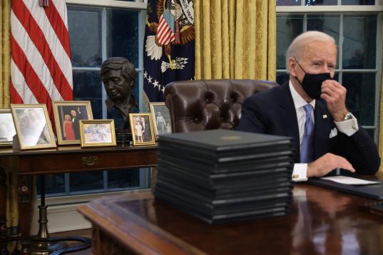Biden, en su escritorio, con las fotos familiares de fondo.
