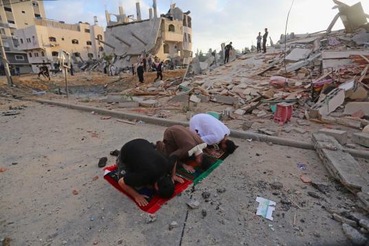 Los palestinos realizan la oración de Eid al-Fitr cerca de las ruinas de los edificios destruidos por los ataques aéreos israelíes en Gaza