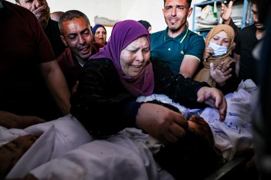 La abuela y los familiares de tres niños de la familia Al-Tanani, muertos en un ataque aéreo israelí, lloran sobre sus cuerpos, antes de su entierro en Beit Lahya, en el norte de la Franja de Gaza, el 14 de mayo de 2021.