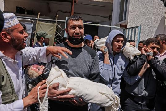 Los palestinos llevan el cuerpo envuelto del niño Ibrahim Alrantisi, muerto en un ataque aéreo israelí, antes de su entierro en Rafah, en el sur de la Franja de Gaza, el 14 de mayo de 2021.