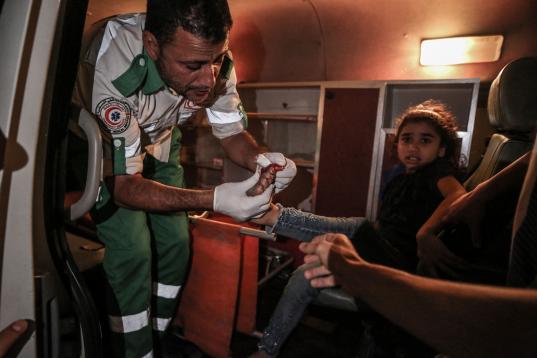 El personal médico ayuda a los civiles palestinos heridos después de que un edificio llamado "Hanady" en el barrio de Al-Rimal colapsara debido al ataque de aviones de combate israelíes en la Franja de Gaza