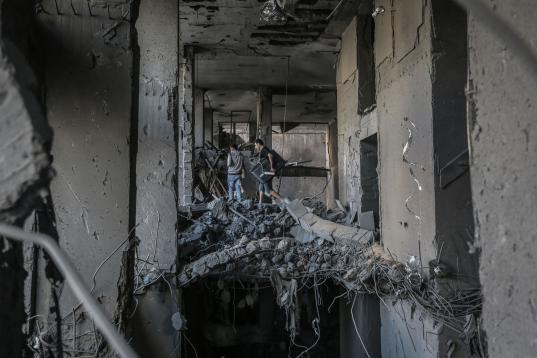 Los palestinos inspeccionan la torre Al-Jawhara, gravemente dañada, en la ciudad de Gaza después de que fuera golpeada por ataques aéreos israelíes en medio de la escalada de violencia israelí-palestina.