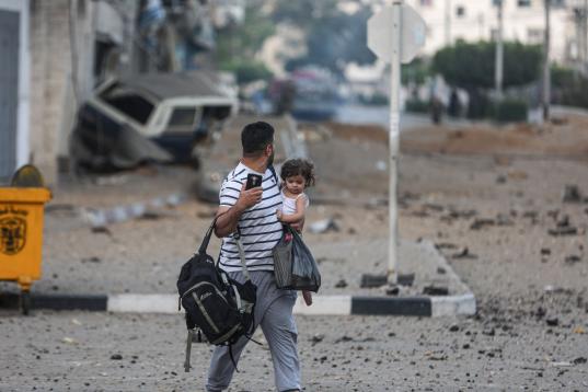 Un padre palestino y su hija abandonan su vecindario para dirigirse a un lugar más seguro mientras los aviones de combate israelíes continúan los ataques aéreos en la Franja de Gaza