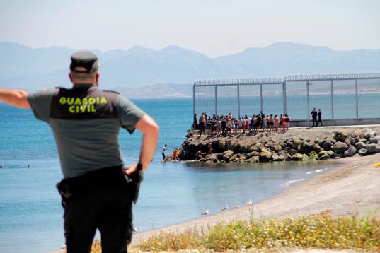 Un agente de la Guardia Civil observa a inmigrantes marroquíes llegados a nado este lunes a Ceuta.