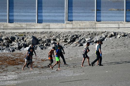 Algunos jóvenes hablan con la Guardia Civil tras llegar a nado a Ceuta.