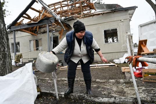 Una mujer trata de recoger lo que queda de una casa prácticamente destruida tras una explosión