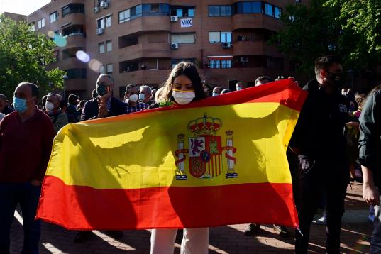 A supporter of far-right party Vox holds a Spanish flag during the presentation of Vox candidate for Madrid Regional election in the Madrid's suburb of Vallecas on April 7, 2021. (Photo by JAVIER SORIANO / AFP) (Photo by JAVIER SORIANO/AFP via G...