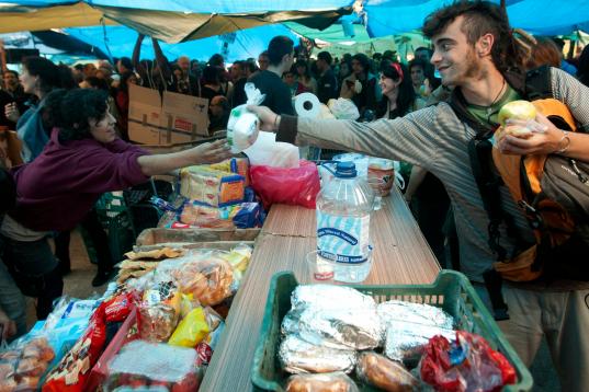Uno de los rasgos más distintivos de aquella acampada fue la solidaridad entre los manifestantes y la organización de la vida diaria en Sol. En la imagen, una de las mesas de reparto de comida gestionadas por los protestantes. 