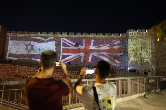 Una de las murallas de la Ciudad Vieja de Jerusalén, con las banderas israelí y británica proyectadas.