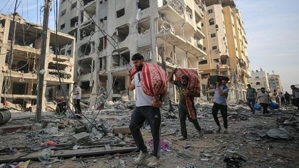 Ciudadanos gazatíes abandonan sus hogares devastados tras los bombardeos israelíes en respuesta al ataque de Hamás, con las pocas pertenencias que pueden cargar.