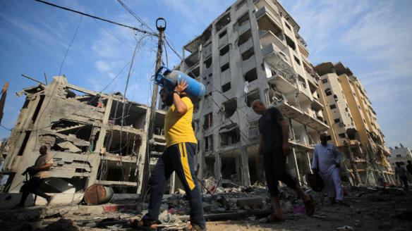 Un grupo de hombres carga con bombonas de butano por las calles destruidas de Gaza.