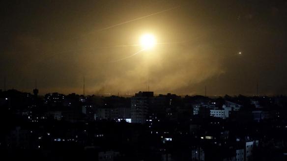 Una bengala israelí ilumina el cielo de una Gaza a oscuras.