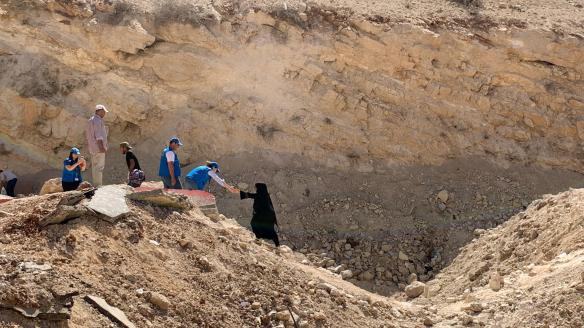 Una familia cruza el cráter dejado tras un bombardeo israelí en la frontera entre Libia y Siria.