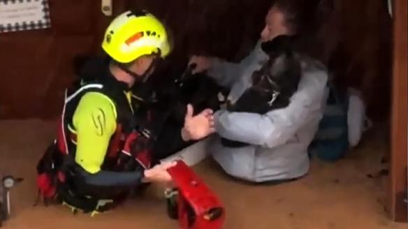 Captura de video que muestra un integrante de las fuerzas de socorro rescatando a una mujer dentro de una inundación en Valencia.