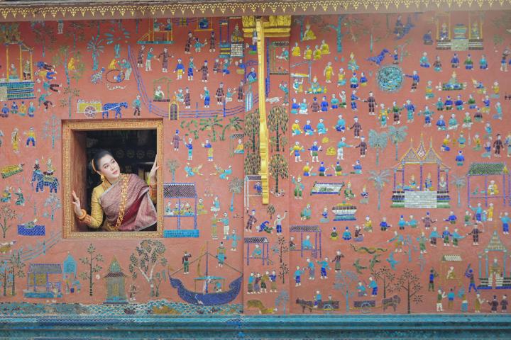 Una mujer asomada por la ventana de un templo en Wat Xieng Thong, Luang Prabang, Laos.