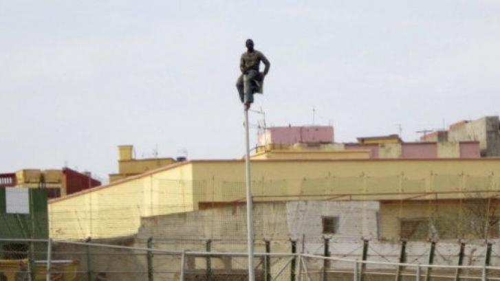 Un inmigrante baja de una farola tras cuatro horas subido a ella junto a la valla de Melilla