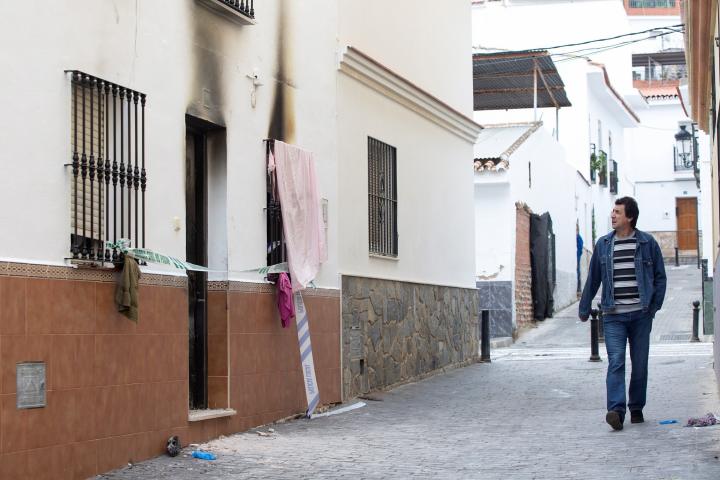 Un hombre pasa por delante de la vivienda donde se registró un incendio en la madrugada de este domingo en la localidad malagueña de Cártama. 