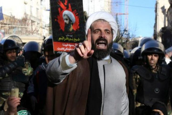 Surrounded by policemen, a Muslim cleric addresses a crowd during a demonstration to protest the execution of Saudi Shiite Sheikh Nimr al-Nimr, shown in the poster in background, in front of the Saudi embassy in Tehran, Iran, Sunday, Jan. 3, 201...